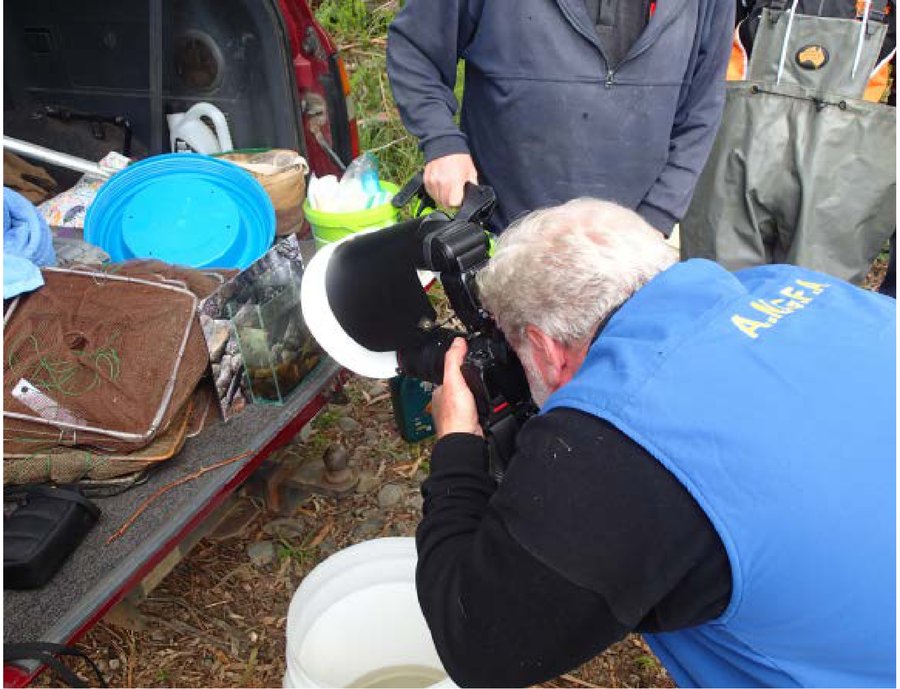 John Lenagan crouched at his tailgate rig with others gathered round